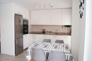 a kitchen with white cabinets and a table and chairs at Ekilore - Basquenjoy in Hondarribia