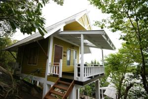 a small yellow house with a white porch and stairs at Cocohut Beach Resort Koh Phangan in Haad Rin