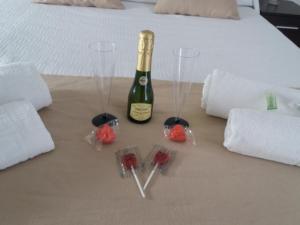 Una botella de vino y tres copas de vino en una cama. en Hospederia Islasol, en San Fernando