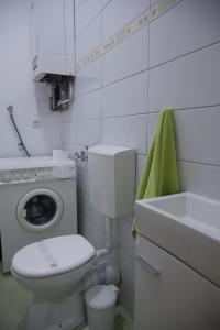 a white bathroom with a toilet and a washing machine at Station in Osijek