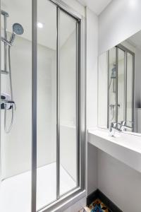 W łazience znajduje się prysznic, umywalka i lustro. w obiekcie hotelF1 Genève Saint Julien en Genevois w mieście Viry