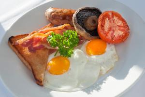 einen Teller Eier und Toast mit Wurst und Tomaten in der Unterkunft Langrish House in Petersfield