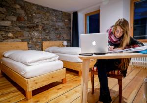 a woman sitting at a table with a laptop at Bed&Bike Tremola San Gottardo in Airolo