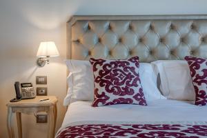 Schlafzimmer mit einem Bett mit lila und weißen Kissen in der Unterkunft Borgo La Chiaracia Resort & SPA in Castel Giorgio