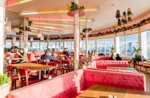 a restaurant with red chairs and tables and windows at GALAAXY Mountain Hostel--Nur mit der Gondelbahn Erreichbar in Laax