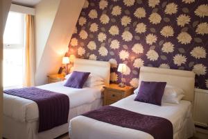2 łóżka w pokoju hotelowym z fioletowymi ścianami w obiekcie Furzedown Hotel w mieście Great Yarmouth
