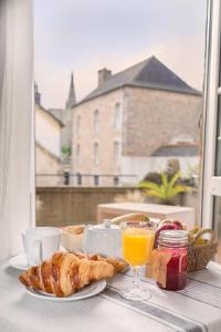 une table avec une assiette de nourriture et un verre de jus d'orange dans l'établissement La Demeure, à Guingamp