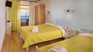 a bedroom with two beds with yellow sheets and a balcony at Pharos Rooms in Ilia