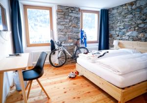 a bedroom with a bed and a desk and a bike at Bed&Bike Tremola San Gottardo in Airolo