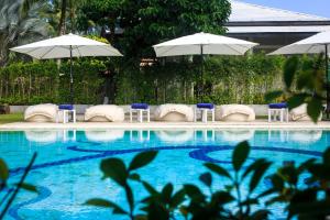 una piscina con sillas y sombrillas junto a ella en The Anda Mani Khaolak Beachfront Villas en Khao Lak