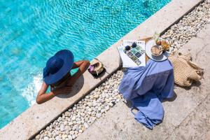 a woman in a blue hat sitting next to a swimming pool at The Anda Mani Khaolak Beachfront Villas in Khao Lak