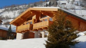 ツェル・アム・ゼーにあるSki-N-Lake Chalet Oneの雪の中にバルコニーが付くログキャビン