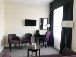 a hotel room with a desk and purple chairs at Hythe Imperial Hotel, Spa & Golf in Hythe