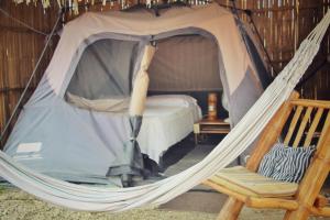 ein Zelt mit einem Bett und einem Stuhl in einem Zimmer in der Unterkunft Cabalonga EcoAdventure in Puerto Cayo