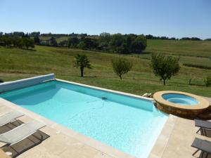 a large swimming pool with a seat and chairs at Gite Stone & Spa in Chasselay
