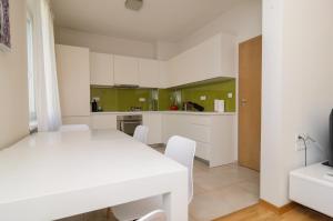 una cucina con tavolo bianco e armadi verdi di Rise & Shine Sofia Luxury Apartment a Sofia