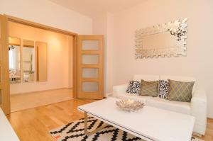 uma sala de estar com um sofá branco e uma mesa em Rise & Shine Sofia Luxury Apartment em Sófia
