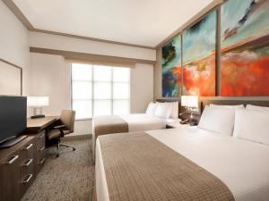a hotel room with two beds and a flat screen tv at Buena Vista Suites Orlando in Orlando