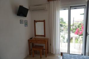 a bedroom with a table and a mirror and a sliding glass door at Arillas Studios in Arillas