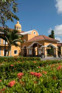a large yellow building with a palm tree and flowers at Amatique Bay Hotel in Puerto Barrios