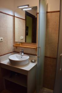 a bathroom with a sink and a shower with a mirror at Hostal Rural Molino Del Bombo in Aracena