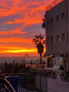 um pôr do sol na praia com um edifício e uma palmeira em Su Casa at Venice Beach em Los Angeles