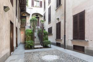 a narrow alley in an old building with plants at Stylish Suite in Fashion District - Corso Venezia in Milan