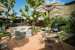 un patio con sillas, mesas y sombrillas en Ristolocanda Grani Di Pepe en Flaibano