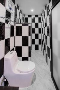 a bathroom with a toilet and a black and white checkered wall at Numjaan Resort in Krabi town