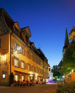 a building with tables and chairs on a street at night at Hotel Garni Krone in Radolfzell am Bodensee