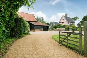 a dirt road with a fence and a house at Corner Farm Barn in Halesworth