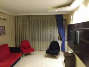 sala de estar con 2 sillas rojas y TV en Grand Ocakoğlu Hotel, en Izmir