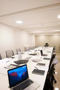 Hotel 6 de Octubre في بوينس آيرس: قاعة اجتماعات كبيرة مع طاولة طويلة مع أجهزة اللاپتوپ