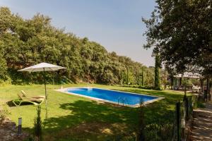 uma piscina num quintal com um guarda-chuva em Casa La Viña em Pedroso de Acim