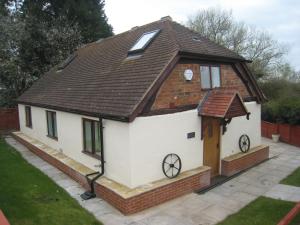 a small white house with a brown roof at Romeo Cottage - Sleeps 4 - Open Plan Barn - Private Hot Tub & Garden in Stratford-upon-Avon