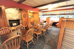 a restaurant with wooden tables and chairs and a fireplace at Alexander's Lodge in Ashford