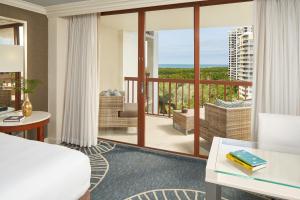 a hotel room with a bed and a balcony at Naples Grande Beach Resort in Naples