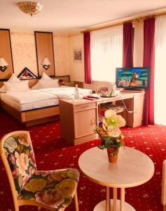 プリュムにあるLandhotel am Wenzelbachのベッド、テーブル、椅子が備わるホテルルームです。