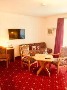 プリュムにあるLandhotel am Wenzelbachのリビングルーム(ソファ、テーブル、椅子付)