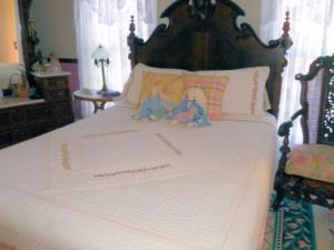 a bedroom with a white bed with a wooden headboard at Belle Aire Mansion Guest House in Galena