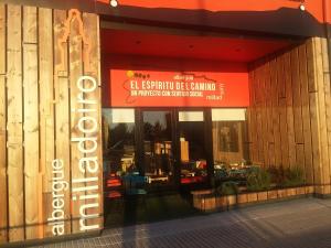 una tienda frente a un edificio con un cartel. en Albergue Milladoiro, en Milladoiro