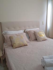 Una cama blanca con cuatro almohadas encima. en Apartamento Beira-Mar, en Balneário Camboriú