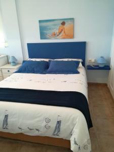 a bedroom with a blue and white bed with a painting at apartamento junto al mar in Cullera