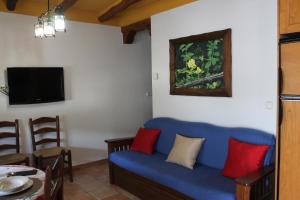 Suite Castillejo في كابيليرا: غرفة معيشة مع أريكة زرقاء مع وسائد حمراء