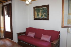 a red couch in a room with a painting on the wall at La Tila in Capileira