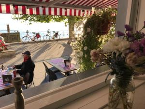 una mujer sentada en una mesa frente a una ventana en Hotel Seepromenade, en Meersburg