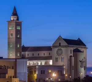 a large building with a clock tower at night at La mia casa era sul porto in Trani