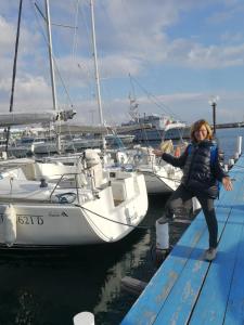 a woman standing on a dock next to a boat at La mia casa era sul porto in Trani