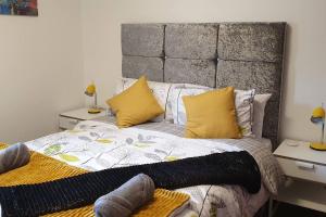 a bedroom with a large bed with yellow pillows at The Beach Apartment, near Outlander location in Kirkcaldy