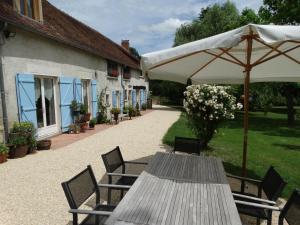 a wooden table with an umbrella next to a building at B&B Le Corbier in Herry